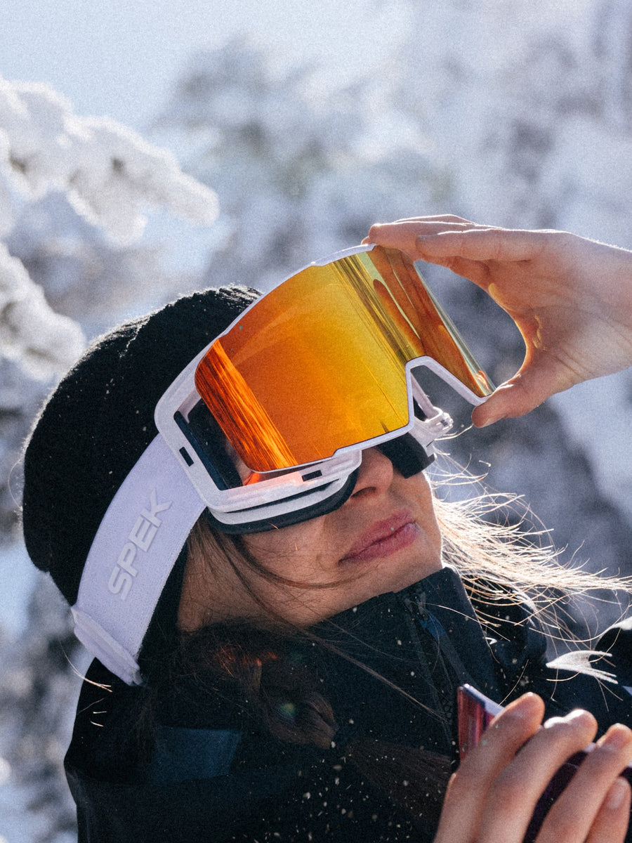 Skieuse qui décroche la lentille aimantée de sa lunette SPEK